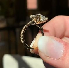 a person holding an engagement ring with a diamond in it's middle and the other hand