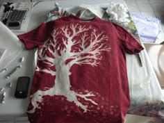 a t - shirt with a tree on it sitting on a table next to other items