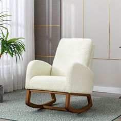 a white chair sitting in front of a window next to a green potted plant