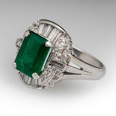 This shimmering ring is centered with an emerald cut emerald, weighing 2.57 carats, in a four-prong setting. The emerald is surrounded by eighteen (18) channel set tapered baguette cut diamonds, and twenty-eight (28) prong set round brilliant cut diamonds. The ring measures 16.0mm at the top, rises 10.5mm above the finger, tapering to 2.5mm wide and 1.1mm thick at the base of the shank. The ring is crafted in platinum and is currently a size 7. Timeless Emerald Ring With Radiant Cut, Elegant Baguette Cut Emerald Ring For May Birthstone, Elegant Emerald Baguette Cut Ring, Platinum Emerald Cut Ring With 17 Jewels, Octagon Emerald Ring In Platinum, Fine Jewelry, Octagon Emerald Ring In Platinum, Gia Certified Timeless Octagon Emerald Ring, Elegant Gia Certified Emerald Cluster Ring, Formal Emerald Birthstone Ring