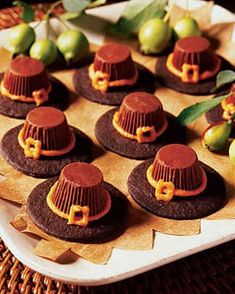 chocolate desserts with orange icing and hats on a tray next to pears