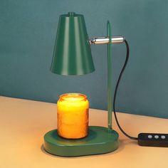 a yellow jar sitting on top of a green table next to a lamp and remote control