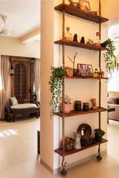 a living room filled with lots of furniture and plants on top of wooden shelving