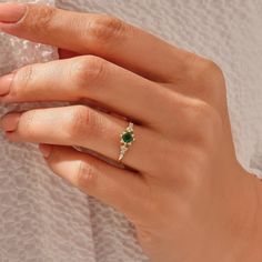 a woman's hand with a ring on it and a green stone in the middle