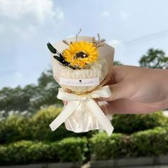 a person holding a sunflower bouquet in their hand