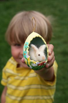 a little boy holding up a small ornament with a white rat in it