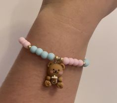 a person wearing a bracelet with a teddy bear charm on it's wrist,