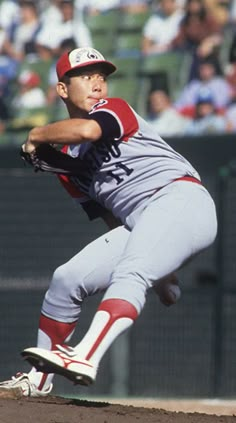 a baseball player pitching a ball on top of a field in front of a crowd