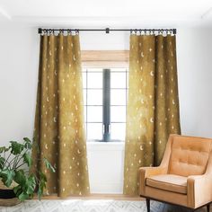 an orange chair sitting in front of a window next to a green potted plant