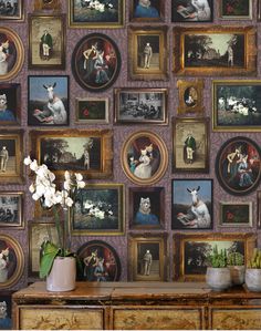 a wall with many pictures and flowers in vases on top of a wooden dresser