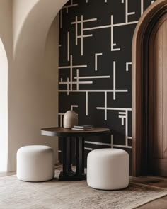 two white stools sitting on top of a rug in front of a black wall