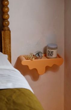 an orange shelf on the wall next to a bed