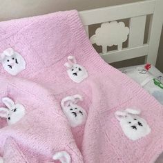 a pink blanket with white teddy bears on it is laying next to a wooden headboard