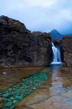 there is a small waterfall coming out of the rocks