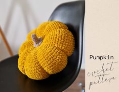 a knitted pumpkin sitting on top of a black chair next to a sign that says pumpkin in crochet pattern