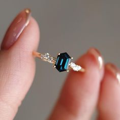 a woman's hand holding a blue and white diamond ring