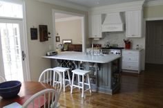 a large kitchen with white cabinets and wooden floors is pictured in this image from the dining room