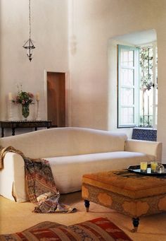 a living room filled with furniture next to a window covered in curtains and rugs