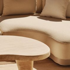 a couch and table sitting on top of a wooden floor next to each other in front of pillows