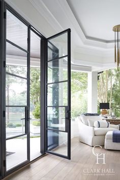 a living room filled with white furniture and lots of glass doors that open up to the outside