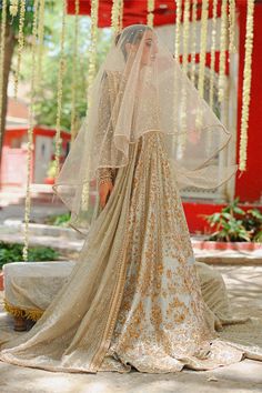 "Exude elegance in this metallic silver hued peshwas cut from tissue, featuring a scalloped hem and detailed zardoze work in a silver and gold composition. A tissue dupatta with sprinkled sequins and zardoze worked borders is paired with a matching handworked tissue brocade lehnga." Gold Jamawar Anarkali Set With Intricate Embroidery, Gold Gown With Intricate Embroidery In Chinon, Silver Anarkali Set For Eid, Elegant Unstitched Silver Lehenga, Silver Designer Salwar Kameez For Eid, Designer Silver Sharara For Festive Occasions, Gold Jamawar Anarkali Set With Resham Embroidery, Bollywood Silver Salwar Kameez For Eid, Silver Bollywood Sharara For Eid