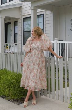 Expertly crafted with a peachy floral chiffon fabric, this midi dress features delicate puff sleeves, a smocked back zipper, and tiered design. Perfect for any occasion, this dress combines style and comfort for a flawless look. peachy floral print chiffon midi length puff sleeves square neckline smocked bodice back zipper closure true to size hand wash cold model is wearing a small and model is 5'5" Flowy Midi Dress With Smocked Back For Garden Party, Garden Party Puff Sleeve Midi Dress With Gathered Neckline, Spring Feminine Puff Sleeve Dress With Smocked Back, Feminine Spring Puff Sleeve Dress With Smocked Back, Puff Sleeve Midi Dress With Ruffles For Garden Party, Midi-length Puff Sleeve Dress For Garden Party, Midi Length Puff Sleeve Dress For Garden Party, Midi Chiffon Dress With Ruffles For Garden Party, Spring Garden Party Puff Sleeve Dress With Smocked Back