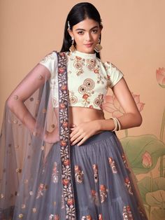 Perfectly pretty and eye-catchy gracefully adorned with this attractive grey color lehenga is formed with net material designed with mirror work, thread embroidery, and sequin work. This grey lehenga arrives with a ivory color art silk material choli made with embroidery and mirror work. It also comes with a grey color net material dupatta created with thread embroidery and sequin work. This grey lehenga is stitched and can be customized up to 42 inches. The choli will be fully stitched material Sangeet Function, Grey Lehenga, Embroidery Mirror Work, Flared Lehenga, Dori Embroidery, Ghaghra Choli, Embroidery Mirror, Bridesmaid Lehenga, Mirror Work Blouse