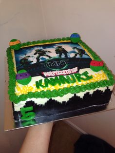 a person holding up a cake that is decorated with video games and numbers on it