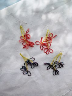 three pieces of string art sitting on top of a white cloth covered tablecloth with red, yellow and blue strings attached to them