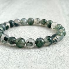 Features: ~ 6mm, 8mm or 10mm Moss Agate beads ~ Stretchy cord; simply slide bracelet on and off wrist ~ Comes packaged in a re-usable microfiber pouch To ensure the perfect fit, please use the bracelet sizing instructions found in the photo gallery. Moss Agate - Moss agate is said to encourage tranquility and emotional balance. Moss agate is the perfect stone for those who experience strong aggression or overly nurturing emotions, helping to balance male and female energies whenever they become Green Beaded Bracelets, Slide Bracelet, Mens Beaded Bracelets, Agate Beads, Green Bead, Moss Agate, Bead Bracelet, Stretch Bracelet, Bracelet Sizes