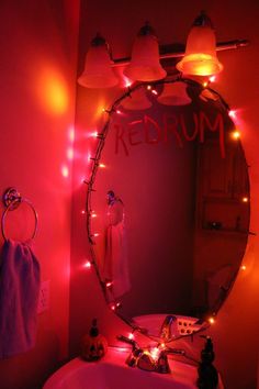 a bathroom sink under a lighted mirror with the word redrum written on it