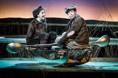 two people sitting on top of a boat with spoons in front of them and one person wearing a hat