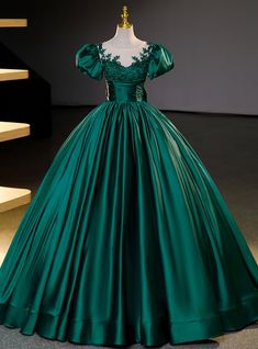 Dazzle the room with elegance in this luxurious emerald Quinceanera gown! Exquisite in its craftsmanship, the dress boasts a fitted bodice adorned with intricate floral appliques that cascade gently over the shoulders, creating an image of garden-esque splendor. The off-the-shoulder sleeves add a touch of classic romance, while the full, flowing skirt, crafted from sumptuous satin, creates a stunning silhouette that's both timeless and regal. Cinched at the waist with a ruched belt detail, this gown accentuates your figure before it balloons into a grandiose, floor-length skirt, ensuring every step you take is a statement of grace. This dress is not only a piece of clothing but a keepsake that embodies the celebration of youth and dreams blossoming into reality.Silhouette:ball gownHemline: Formal Dress Short, Long Tulle Skirt, Green Ball Gown, Occasion Dresses Wedding Guest, Tulle Long Skirt, Satin Ball Gown, Formal Dresses With Sleeves, A Line Evening Dress, Elegant Attire