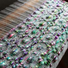 a close up view of a weaving machine with colorful beads on the fabric and thread