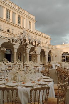 the tables are set with white flowers and place settings for an elegant wedding reception in front of a large building