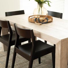 a wooden table with black chairs and a vase on it