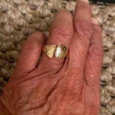 an older person's hand with a gold ring on top of it and a diamond in the middle