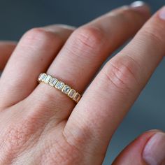 a woman's hand with a gold ring on top of her finger and two diamonds in the middle