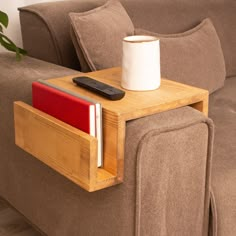 a wooden table with a remote control and a cup on it next to a couch