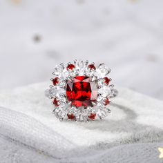 Displaying vivacious feminine flair, this striking fashion ring highlights all that makes her truly exceptional. Crafted in sterling silver, this pretty and unconventional look showcases an cushion cut center stone. Oval cut stones, white round stones and red round stones wrap the centerpiece in a sparkling embrace. Buffed to a brilliant luster, this fabulous conversation piece is sure to be admired often.Carat Weight: 3.7 ctStone Size: 8*8 mmStone Type: Jeulia® StoneNumber of Stones: 1 Stone Color: Garnet RedStone Shape: CushionCarat Weight: 0.62 ctStone Size: 2.3,2 mmStone Type: Jeulia® StoneNumber of Stones: 9 Stone Color: Garnet Red, Diamond WhiteStone Shape: RoundWeight: 6.48 gWidth: 16.4 mmHeight: 8.3 mmThickness: 2.8 mmMaterial: 925 SilverPlating Color: Silver White Ruby Ring With Center Stone, Luxury Cushion Cut Ruby Ring With Halo Setting, Elegant Lab-created Ruby Diamond Ring With Accent Stones, Red Diamond Ring With Brilliant Cushion Cut, Red Cushion Cut Brilliant Diamond Ring, Elegant Cushion Cut Ruby Ring For Wedding, Elegant Rings With Lab-created Ruby And Accent Stones, Elegant Cushion Cut Ruby Promise Ring, Red Cushion Cut Diamond Ring With Brilliant Cut