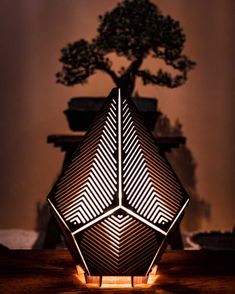 an unusual lamp is lit up on the table with a tree in the back ground