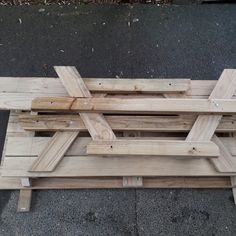 a wooden bench sitting on top of a sidewalk next to a parking lot with no one around it