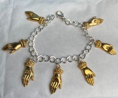 "Victorian style cuffed hand gold tone charm bracelet. Elegant with the hand being the heart of special occasions like engagement or weddings, mystical for millennia or simply to give someone a hug  Using 7 charms,of hands The bracelet has a lobster claw clasp. A lovely bracelet , an ideal quirky present . There are also co-ordinating earrings listed for pierced ears as well as a brooch See also silver tone versions  All the charms are single sided. Measurement : The charm is 2.5 cm / 1\" long. The chain is available in lengths 19-21cm If you need a shorter chain please contact me but the open links mean that you can hook in the lobster claw clasp where it suits. If no length is specified I will send the 20cm standard length" Gold Chain Bracelet With Extender In Sterling Silver, Spiritual Metal Chain Bracelet With Lobster Clasp, Handmade Symbolic Gold Charm Bracelet, Symbolic Handmade Gold Charm Bracelet, Hand Cast Metal Bracelets Gift, Gold Spiritual Charm Bracelet With Lobster Clasp, Gold Spiritual Charm Bracelet With Dangling Charms, Gold Symbolic Charm Bracelet, Gold Charm Bracelet With Symbolic Dangling Charms