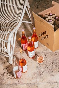 several bottles of wine are sitting on the floor next to a cardboard box and some glasses