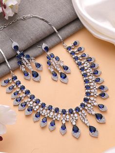 Add a touch of glamour and sophistication with this high quality necklace set in beautiful  sapphire blue stones. The stones in this set bling and look close to the real thing. This set is sure to make heads turn!  It features an adjustable necklace and a pair of earrings. It can be paired perfectly with both ethnic and western outfits.  In case of any queries, please feel free to reach out. Happy shopping! Necklace weight: 70 gms Length :16 inches Adjustable length with a metal chain at the bac Blue Crystal Jewelry Sets For Wedding, Sapphire Jewelry Sets For Wedding, Elegant Blue Bridal Sets Gift, Blue Hand Set Jewelry Sets For Wedding, Sapphire Diamond Necklaces For Weddings, Blue Diamond Jewelry Sets For Wedding, Hand Set Blue Jewelry Sets For Wedding, Blue Hand Set Jewelry For Wedding, Sapphire Jewelry With Sparkling Stones For Wedding