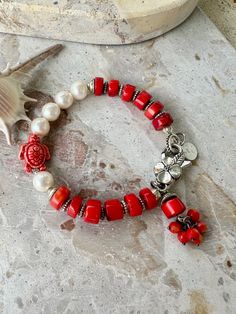 This vibrant coastal bracelet features striking red coral beads paired with elegant white pearls, evoking a bold yet sophistical aesthetic. A detailed silver toned flower charm made up of red coral beads as a focal point. A red turtle bead adds a touch of whimsy and oceanic charm, while small silver spacer accents tie the design together. This bracelet has a perfect coastal summer look. 20cm in length - 8 inches long .  Most of my bracelets can be customer made to fit any size. Coastal Bracelet, Pearl Beaded Bracelet, Coastal Summer, My Bracelets, Coral Beads, Flower Charm, Red Coral, Summer Look, Last Minute Gifts