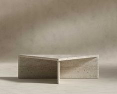 an empty concrete table sitting on top of a white floor next to a gray wall