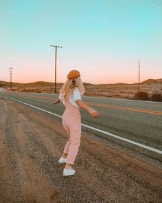 a woman standing in the middle of an empty road