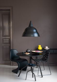 a dining table with two chairs and a black lamp hanging over it in a dark room