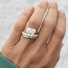 a woman's hand with two gold and white rings on top of her finger